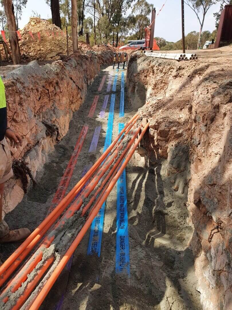 Coloured utility pipes laid in deep trench — CBR Excavations & Drainage